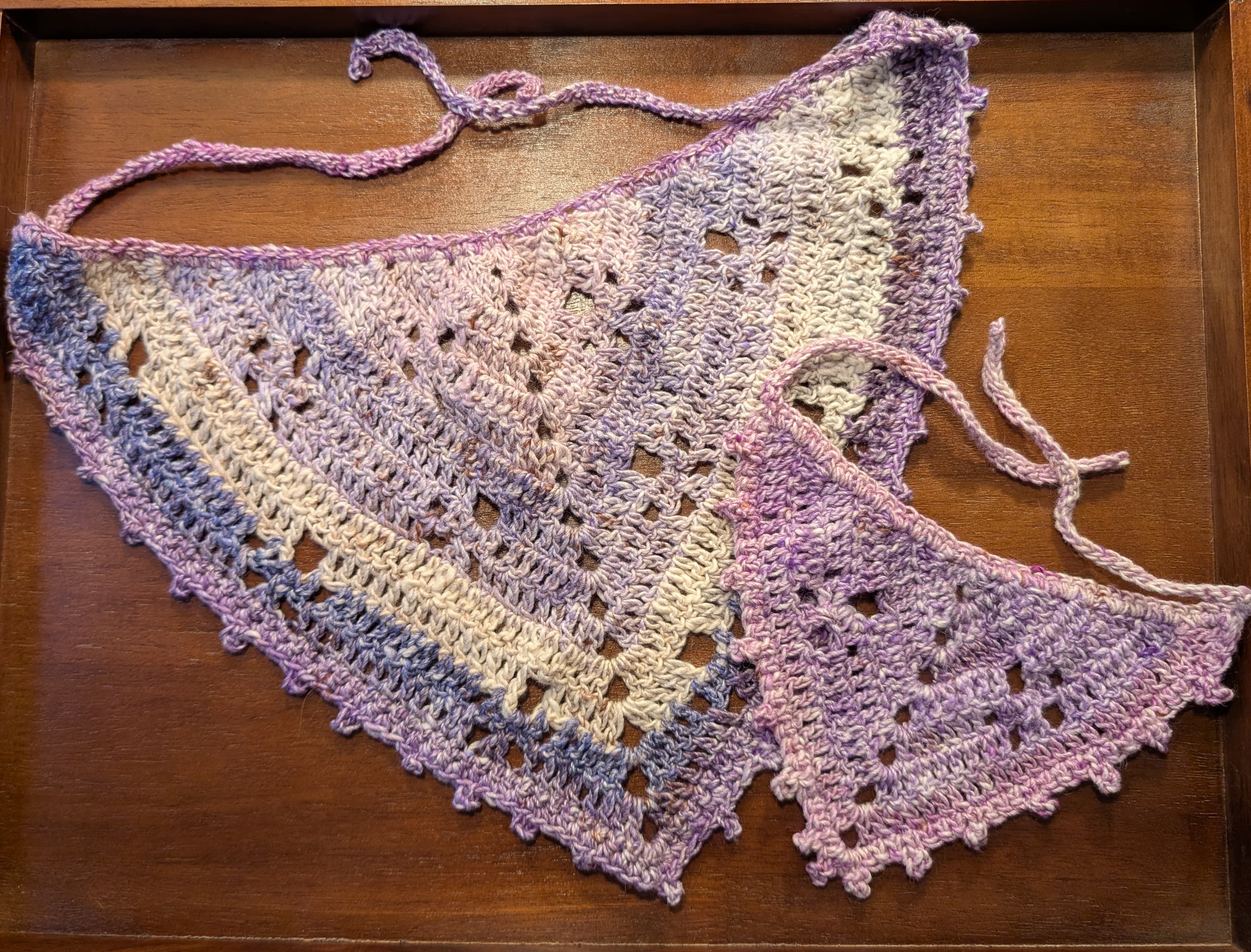 A collection of colorful hand-crocheted bandanas with unique patterns, displayed on a rustic wooden surface